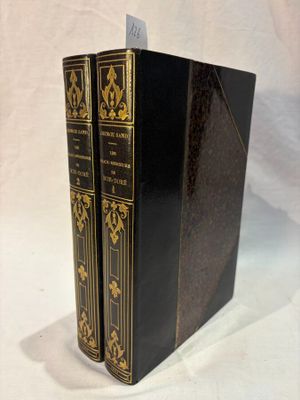 two black books with gold trims are sitting on a white surface