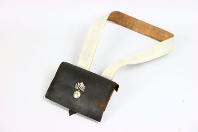 sac à main en cuir avec une bandoulière blanche et une broche en forme d'ananas