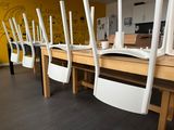 several white chairs are lined up on a wooden table in front of a yellow wall