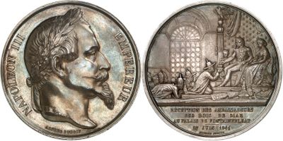 two silver medallions depicting a man with a beard and a woman