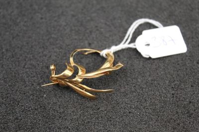 a gold bird brooch with a tag attached to it
