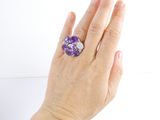 someone is holding a purple ring with a purple flower on it