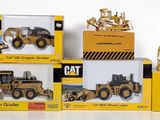 four boxes of toy construction vehicles sitting on a white surface