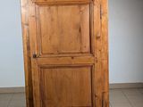 a wooden cabinet in the corner of a room with tile flooring