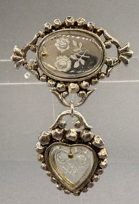 a silver brooch with a picture of a man and a woman on it