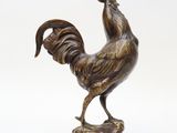 bronze statue of a rooster on a rock on a white background