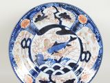 a close up of a blue and white plate with a bird on it