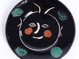une assiette noire ornée d'un motif orange et vert