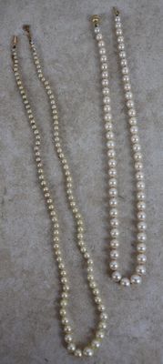 trois colliers de perles posés sur une table, à côté d'une paire de ciseaux