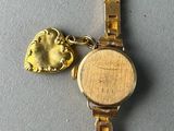 an image of a gold watch with a leaf charm on it