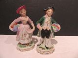 two figurines of a man and a woman standing next to each other