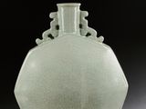 un vase vert posé sur une table sur fond noir
