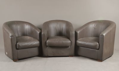 trois fauteuils en cuir marron placés les uns à côté des autres sur un sol blanc