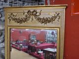 un miroir à cadre doré accroché à un mur rouge