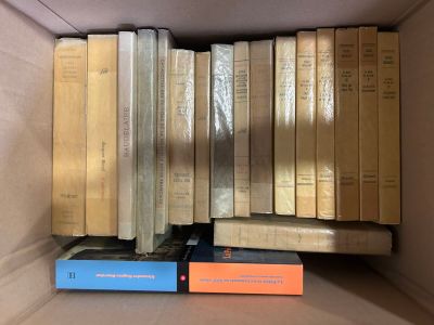 many books in a box that are stacked on top of each other