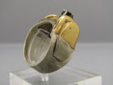 une bague en argent et en or posée sur un socle transparent