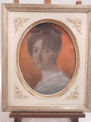 Une vieille photo représentant une femme en robe blanche est posée sur un chevalet en bois.