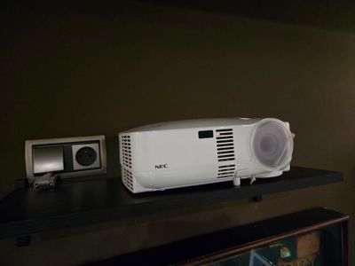 un projecteur blanc posé sur une étagère noire