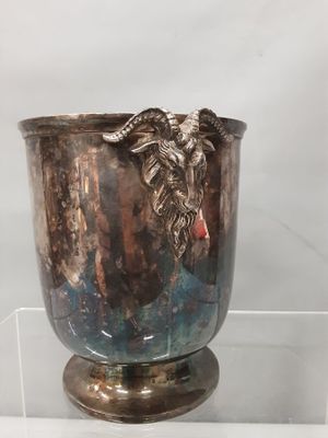 a silver vase with a goat head on it on display