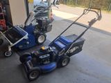 two lawn mowers parked next to each other in a garage