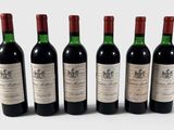 quatre bouteilles de vin sont alignées sur une surface blanche
