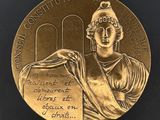 un gros plan sur une médaille d'or, avec une femme tenant un livre