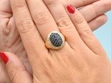 woman ' s hand with red manicured nails and a gold ring with a black stone