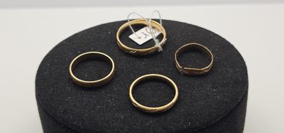 trois bagues en or sont posées sur un porte-bagues noir