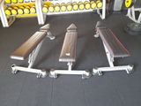 une salle de sport avec une rangée de bancs et une rangée d'haltères