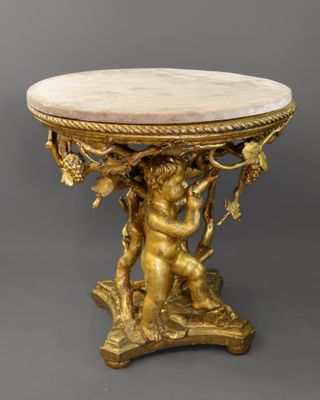 une table en or avec un plateau en marbre sur lequel trône une statue