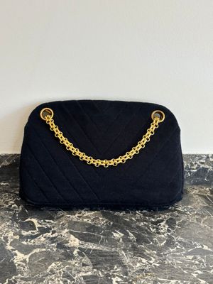 un sac à main noir matelassé muni d'une bandoulière en chaîne dorée