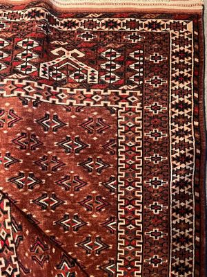 a close up of a red and black rug on a white surface