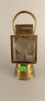a small brass lantern with a green sticker on it