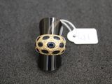 an image of a black and gold ring with a tag on it
