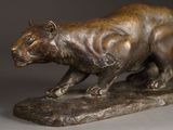 bronze sculpture of a tiger on a rock on a gray background