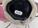 someone is holding a pink and black vase with a tag on it