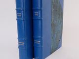 two blue books sitting on top of each other on a white surface