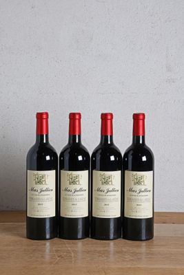 three bottles of wine sit on a wooden table next to a bottle of wine
