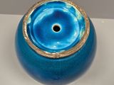 a blue vase with a gold rim sitting on a table