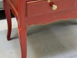a small red desk with a drawer on top of it