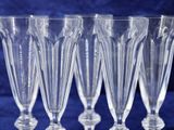 six clear wine glasses lined up in a row on a blue background