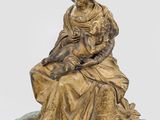 a bronze statue of a woman sitting on a rock