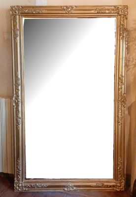 un grand miroir posé par terre à côté d'un vase