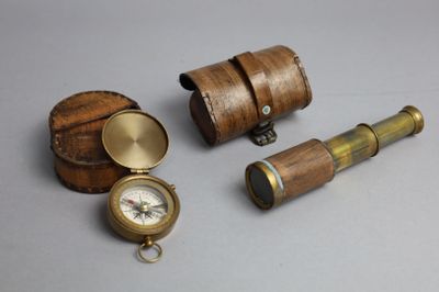 un petit coffret en bois contenant une boussole et d'autres objets, posé sur une table
