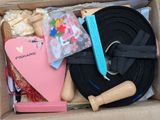 a box with various items in it that include a black belt, a pink heart, and a black ribbon