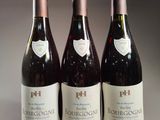 three bottles of red wine are lined up on a table