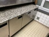 une cuisine équipée d'appareils électroménagers en inox et de plans de travail en granit