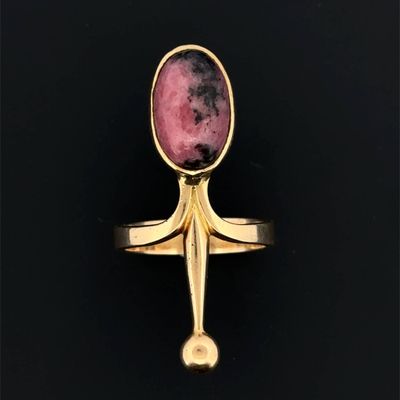 gros plan d'une bague en or avec une pierre rose