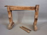 a small wooden table with two nails on it