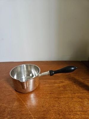 une petite casserole posée sur une table en bois, à côté d'un mixeur